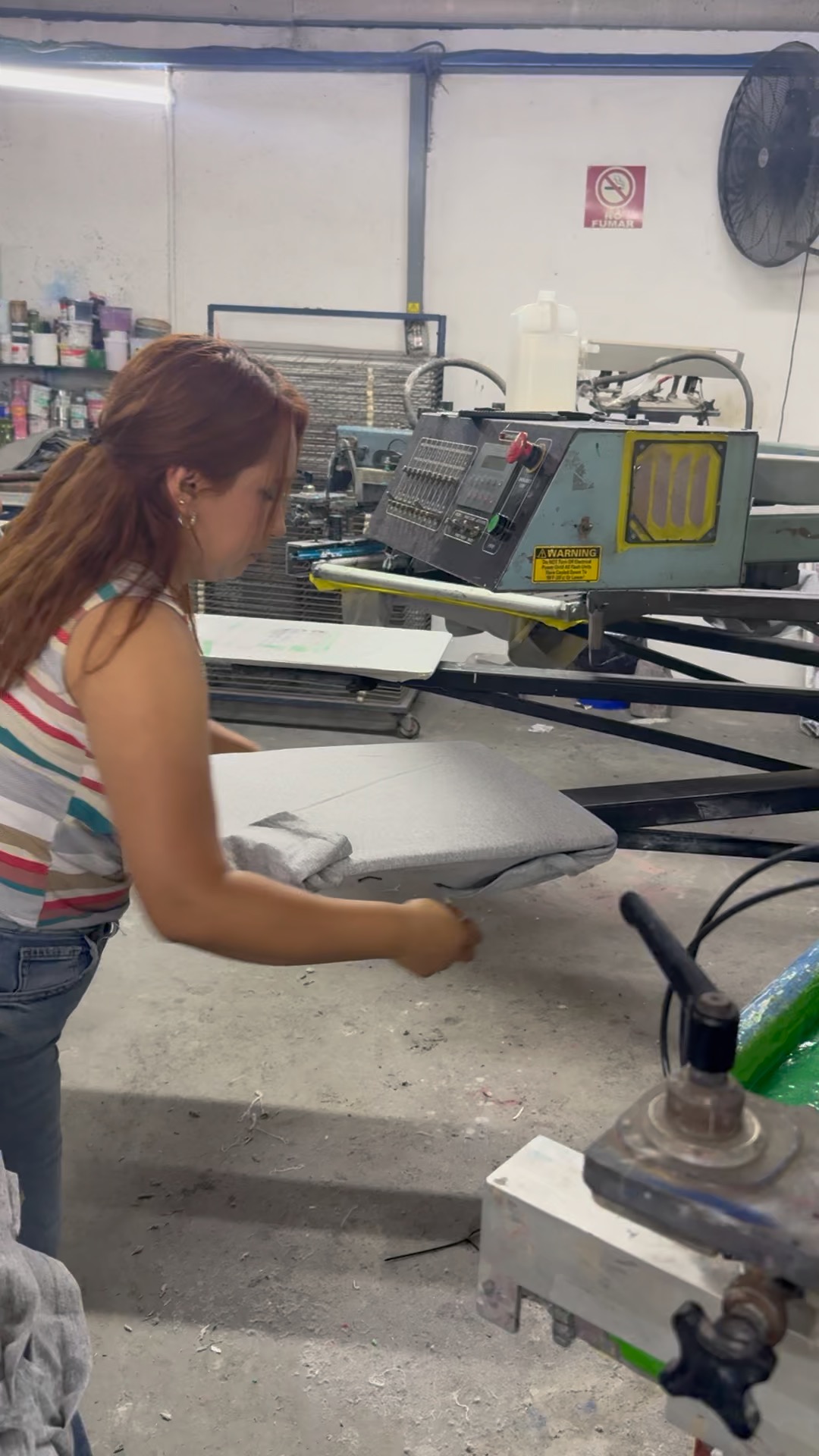 Operaria colocando una prenda en la paleta de la máquina de serigrafía
